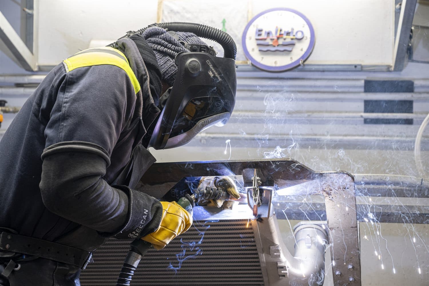 Enfrio operator welding a radiator core in front of the company logo